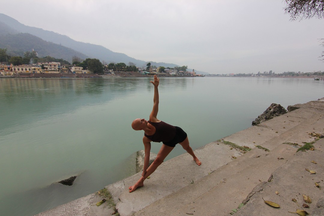 Yoga Utthita Trikonasana, extended Triangle Final Pose front view, by the Ganges in Rishikesh, India